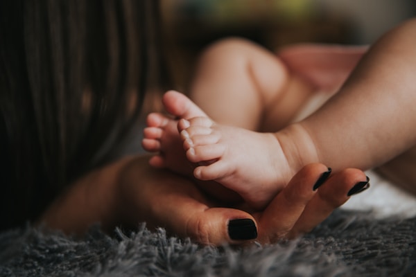 A newborn baby's feet resting in a parent's hand