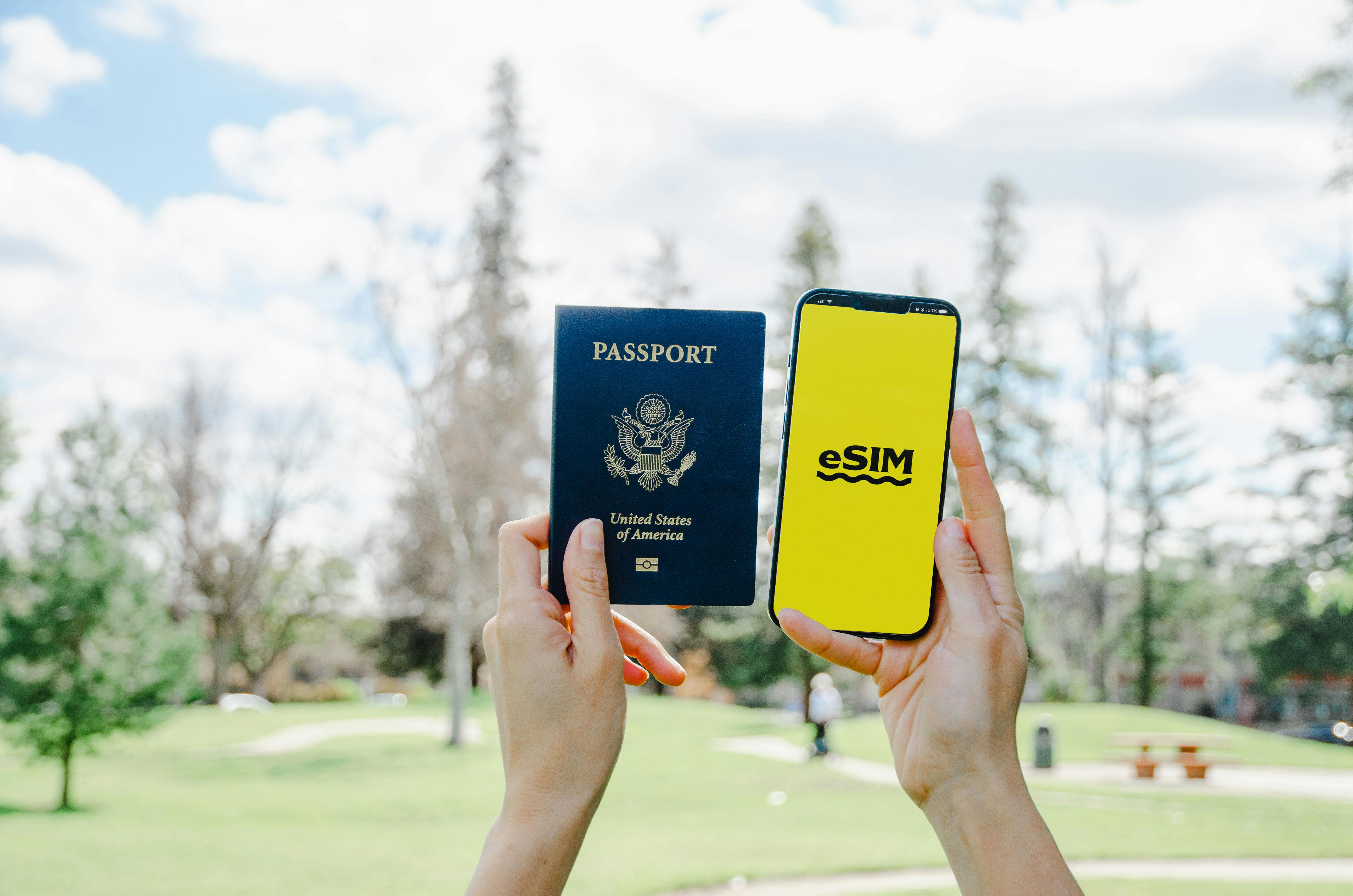 Hands holding a U.S. passport and a phone showing an eSIM screen